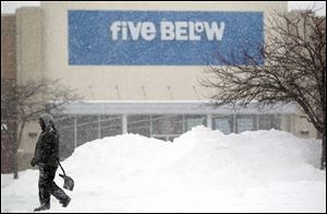 A man walks through while shoveling the parking lot in front of the Five Below shop in Fairview Heights, Ill. 