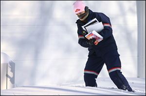 U.S. Postal Service letter carrier Jamie Jasmon struggles through snow and below zero temperatures while delivering the mail Monday in Springfield, Ill.
