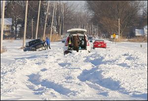 Three vehicles try to dig their way out of the snow on Suder Avenue. near Lotus Drive in Erie, Mich. today.