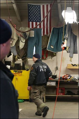 Toledo firefighter Bill Bruss passes by drying firefighting clothing hung inside the truck bay at the Station 9 firehouse in South Toledo.