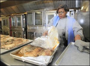 Mary Bourn of Toledo, cooks pork roasts for meals for Wednesday at The Margaret Hunt Senior Center, the site of meal preparation and distribution for area residents in Toledo.