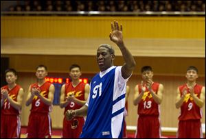 Dennis Rodman waves to North Korean leader Kim Jong Un, seated above in the stands, after singing Happy Birthday to Kim before an exhibition basketball game with U.S. and North Korean players at an indoor stadium in Pyongyang, North Korea on today.