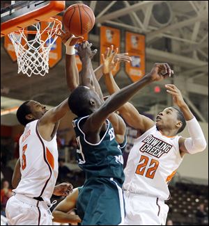 Bowling Green’s Spencer Parker, left, and Richaun Holmes battle Eastern Michigan’s Glenn Bryant for the ball in Wednesday night’s game at the Stroh Center. The Falcons fell to 6-8.