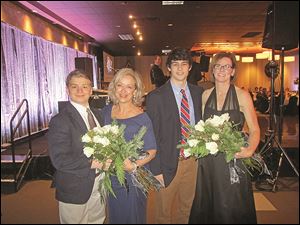 Joe DuPuis,left, and Noah Best, second from right, present flowers to their mothers Carol and Sara who served as volunteer chairpersons of the 2013 An Elegant Knight, a fund-raiser for St. Francis de Sales
