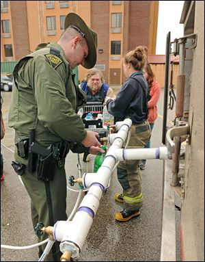 West Virginia State Trooper Nathan Stepp of Charleston fills bottles with water for Homer Larch of Pinch at the Kmart in Elkview W.Va., on Friday.  Emergency crews are setting up water depots at many locations around the state.
