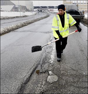 Toledo city worker Paula Williams patches potholes on Berdan Avenue near Detroit Avenue on the city’s north side.