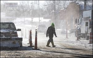 A city worker battles blowing snow in downtown Toledo. Monday’s conditions were blamed on the polar vortex.