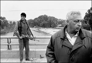 In this March 7, 1984 file photo, an Israeli soldier keeps his finger on the trigger of his assault rifle while Former Defense Minister Ariel Sharon, right, stands on the bridge overlooking the Awali River, Israel's most northerly position in Sidon, Lebanon. 