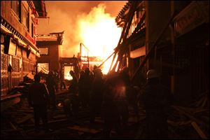Firefighters fortify a wooden building Saturday while a fire ravages ancient Dukezong town in Shangri-la county, in southwestern China's Yunnan province.