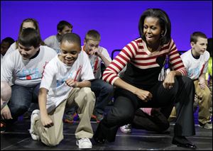 First lady Michelle Obama does the Interlude dance with kids on stage during a Let's Move event with children from Iowa schools, at the Wells Fargo Arena in De Moines, Iowa, in February, 2012.