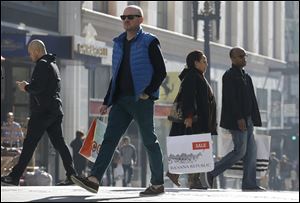 Last minute holiday shoppers carry bags as they cross the street in San Francisco on Christmas Eve.