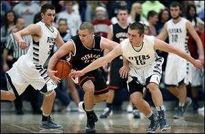 Lake’s Connor Bowen, left, and Cody Witt, right, defend Otsego’s Cody Downs on Tuesday night in Millbury. Bowen scored 20 points and Witt added 17.