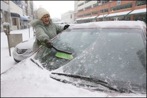 Liz Geniac works to brush the snow off of her car on North Superior Street near Madison as she leaves one job to head to another.