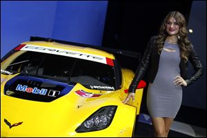 A model poses with a Corvette race car at the North American International Auto Show in Detroit, Monday.
