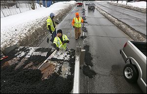 Corey Allison, Paula Williams, and Dwayne Garrett, from left, patch potholes on Berdan Avenue near Detroit Avenue last week.