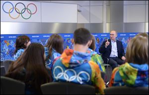 Russian President Vladimir Putin, background right,  speaks at his meeting with Olympic volunteers in the Black Sea resort of Sochi, Russia today.