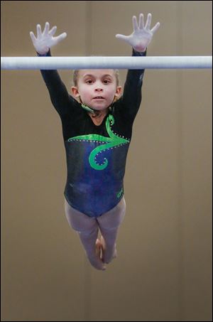 Cali Mitchey, 8, changes bars in the uneven  bars. Unlike high bars and rings, gymnasts must mount uneven bars by themselves instead of being lifted onto them.