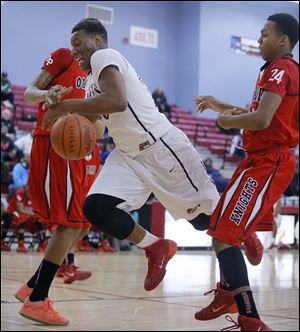 Fadil Robinson of Rogers tries to drive between Oak Park’s Kelvon Fuller, left, and Antonio Davis in Monday’s MLK Classic at Bowsher.