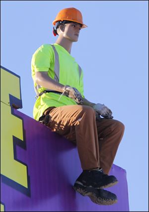 A eye-catching mannequin sits atop a billboard.