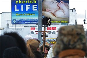 Denny Karl, of Williston, center, held a crucifix aloft during a protest outside the Capital Care Clinic, which provides pregnancy termination services, for the 41st anniversary of the supreme court decision which made abortion legal in the United States.