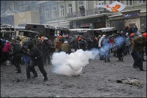 Protesters run away from a stun grenade as they clash with police in central Kiev, Ukraine, early today. Two people have died in clashes between protesters and police in the Ukrainian capital today.