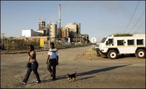 A couple walks with their a dog past the entrance to the Lonmin's platinum mine in Marikana, near Rustenburg, South Africa.