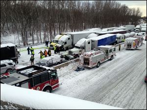 Emergency crews work at the scene of a massive pileup involving about 15 semitrailers and about 15 passenger vehicles and pickup trucks along Interstate 94 Thursday afternoon near Michigan City, Ind.