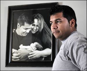 Erick Munoz stands with an undated copy of a photograph of himself, left, with wife Marlise and their son Mateo, in Haltom City, Texas.
