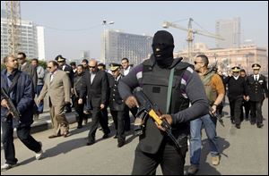 An Egyptian masked policeman guards Cairo's state security chief, Osama al-Saghir, third left, as he visits Tahrir Square on Saturday in Cairo, Egypt.