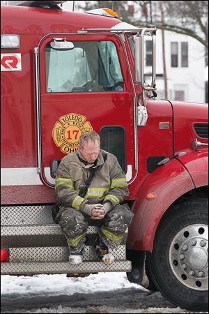 A Toledo firefighter waits outside of 528 Magnolia St. where a blaze consumed an apartment building and claimed the lives of two firefighters.