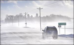 An SUV ventures past the St. Augusta, Minn., city limits sign on Stearns County Road 136 in near white-out conditions Sunday afternoon south of St. Cloud, Minn. 