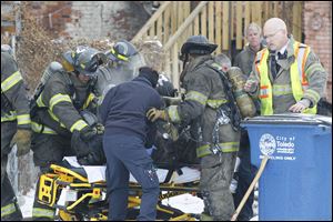 Firefighters and other emergency personnel try to resuscitate a firefighter as he is being taken to get help at the rear of the building at 528 Magnolia. The two firefighters went missing inside during the blaze.