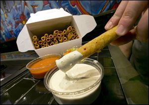 A Buffalo chicken taquito is dipped in bleu cheese dressing.