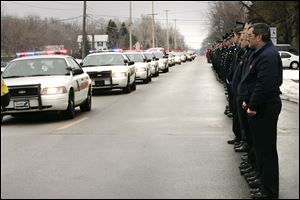 Firefighters and police officers watch the procession to the cemetery during Toledo Detective Keith Dressel’s funeral services.