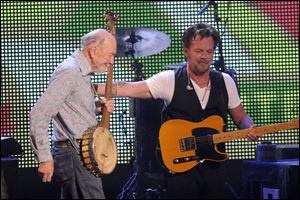 Pete Seeger is welcomed onstage by John Mellencamp during the Farm Aid 2013 concert at Saratoga Performing Arts Center in Saratoga Springs, N.Y. Seeger, an American troubadour, folk singer, and activist, died in New York on Monday at age 94. He had performed in Toledo at least three times.
