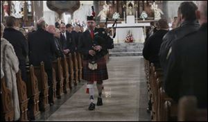 Chief Matt Hart plays Amazing Grace with his bagpipes during mass to honor the lives of Toledo firefighters Stephen A. Machcinski and James Dickman at the Historic Church of St. Patrick in Toledo.