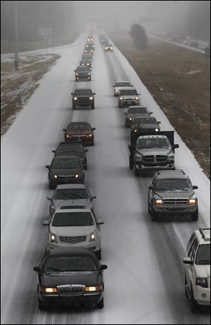Vehicles moves slowly on Interstate 575 in North West Ga., Tuesday near Kennesaw, Ga. Georgians stocked up on ice-melting chemicals, school systems closed, and road crews prepared to clear snow and ice from highways as a winter storm took aim. 