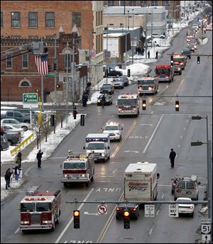 The funeral procession, which was met throughout the route at every overpass by other fire trucks, police cars, or other emergency vehicles, heads down Monroe Street in downtown Toledo.