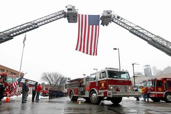 A-fire-truck-passes-under-the-flag-during-the-procession