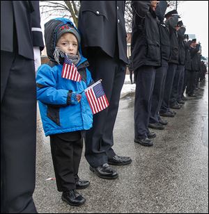 Caden Quinn, 4, joins his father, Pvt. Gary Quinn of the Toledo Fire Department, as the procession passes Station 5. Private Machcinski was a 15-year member of the department.