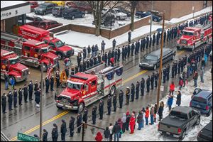 Engine 3 from the Toledo Fire Department, draped in black and purple bunting, carries Pvt. Stephen Machcinski’s coffin past Station 5 on North Ontario Street as the rest of the funeral procession follows. 