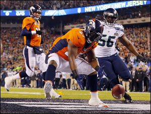 Denver Broncos running back Knowshon Moreno reaches for a loose ball after the snap sailed passed Peyton Manning, left, during the first quarter in Super Bowl XLVIII on Sunday in East Rutherford, N.J. The play resulted in a safety for Seattle.