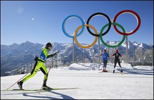 An athlete skis in front of the Olympic rings at the skiing and biathlon center in Polyana, Russia. The Games open on Friday.