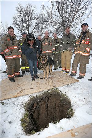 Buffalo, N.Y. Rescue 1 firefighter Michael Paveljack, left,  Mattie Moore, second from,left, and her dog Mack stand by the sink hole.