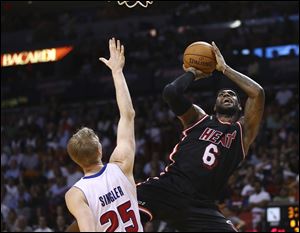 Detroit Pistons' Kyle Singler (25) tries to block Miami Heat's LeBron James (6) during the first half.