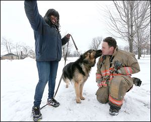Rescue 1 firefighter Michael Paveljack, right, gets a kiss from Mack, the dog he rescued.