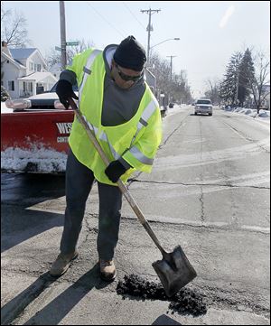Debbie Gray, who works for the city’s Department of Streets, Bridges, and Harbor, patches a pothole on Douglas Avenue near Westbrook Drive in West Toledo.