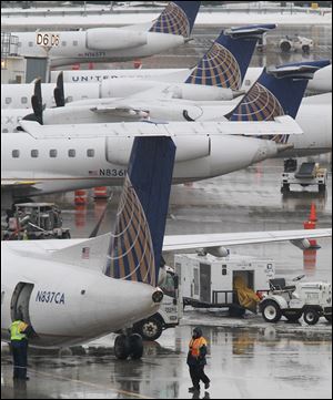 United Airlines baggage handlers prepare to unload a  commuter flight that  landed at Cleveland Hopkins International Airport. United will cut 64 percent of its departures when it drops its Cleveland hub, costing 470 jobs.