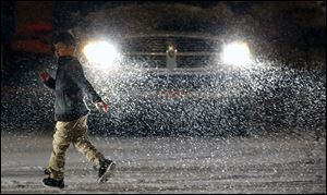 A boy races through the parking lot of Gibsonburg High School to avoid the snow after the Ottawa Hills basketball game, in Gibsonburg, Ohio.