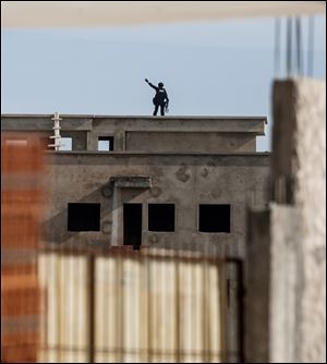 A Tunisian anti-terrorist police forces (BAT) gestures from a rooftop near a house where suspected Islamist militants were hidden in Raoued, near Tunis.